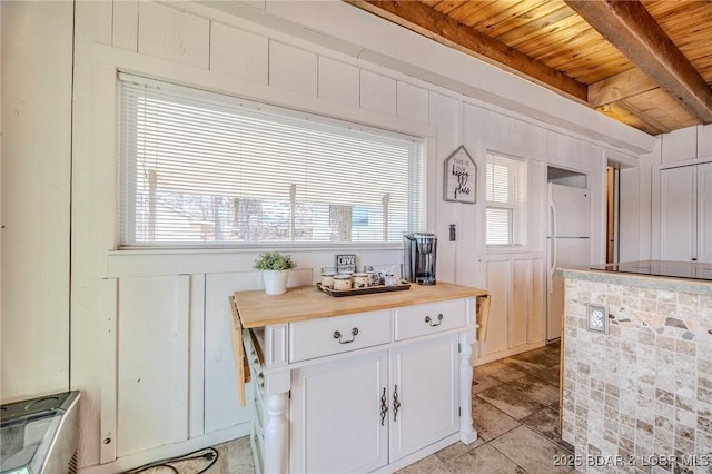 33271 Elaine Rd, Sunrise Beach, MO 65079 - kitchen featuring wood ceiling with exposed beams, freestanding refrigerator, white cabinets, wood counters, and a decorative wall