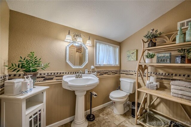 33271 Elaine Rd, Sunrise Beach, MO 65079 - half bathroom with toilet, a textured wall, lofted ceiling, a textured ceiling, and a wainscoted wall