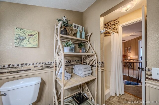 33271 Elaine Rd, Sunrise Beach, MO 65079 - full bath featuring toilet, curtained shower, a wainscoted wall, and a textured wall