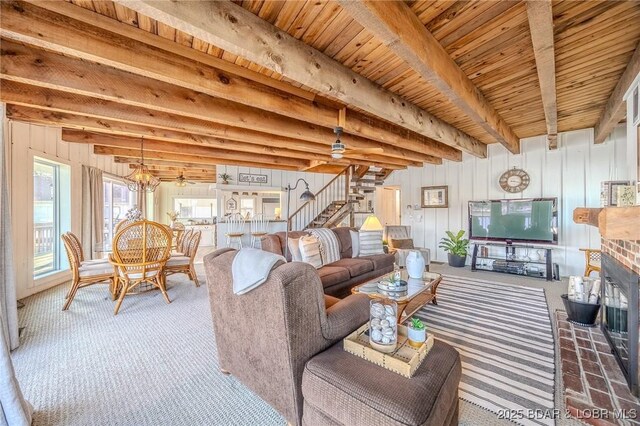 33271 Elaine Rd, Sunrise Beach, MO 65079 - carpeted living room with stairs, wooden ceiling with exposed beams, a fireplace, and a chandelier