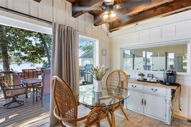 33271 Elaine Rd, Sunrise Beach, MO 65079 - dining room with a ceiling fan, light tile patterned floors, beam ceiling, and wooden walls