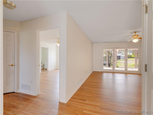 spare room with baseboards, a ceiling fan, light wood finished floors, and visible vents