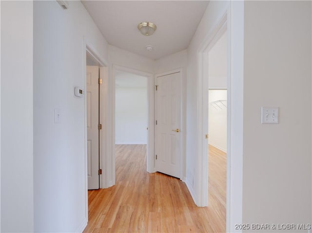 hallway featuring baseboards and light wood-style flooring