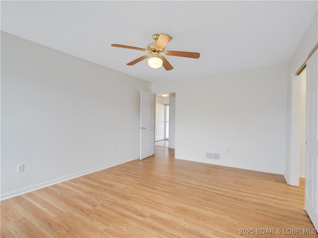 spare room featuring visible vents, a ceiling fan, light wood-style floors, and baseboards