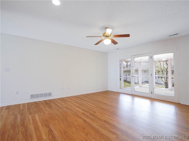 empty room with light wood-style floors, baseboards, a ceiling fan, and visible vents