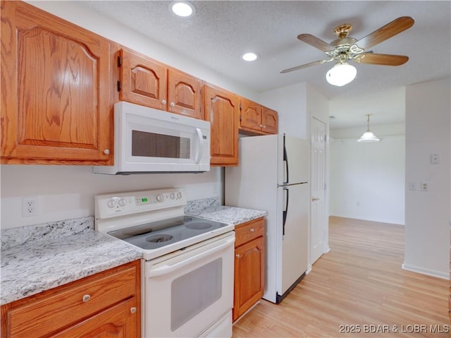kitchen featuring a ceiling fan, brown cabinets, light wood finished floors, recessed lighting, and white appliances