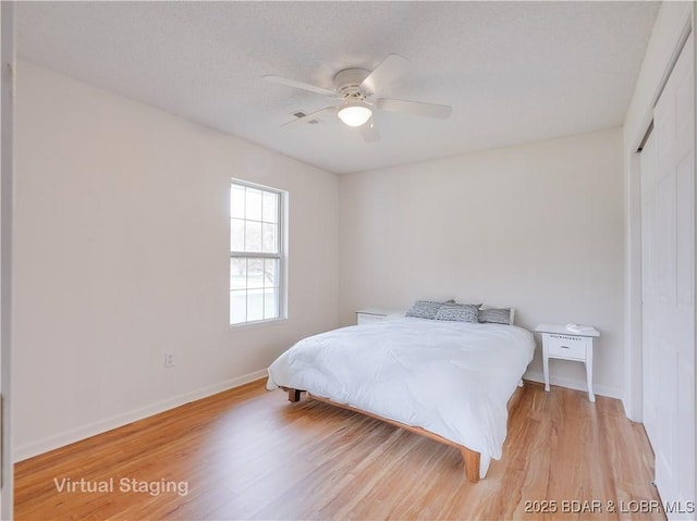 bedroom with light wood-style floors, baseboards, ceiling fan, and a closet
