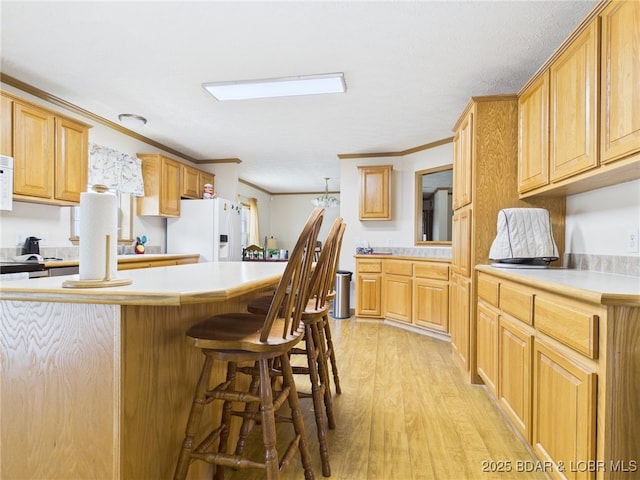 kitchen featuring light wood finished floors, a kitchen breakfast bar, white appliances, crown molding, and light countertops