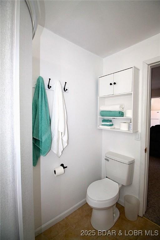 bathroom with toilet, tile patterned floors, and baseboards