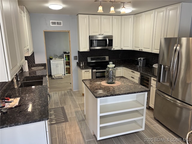 1265 Lick Creek Rd, Edwards, MO 65326 - kitchen with appliances with stainless steel finishes, white cabinetry, decorative backsplash, dark stone counters, and a center island