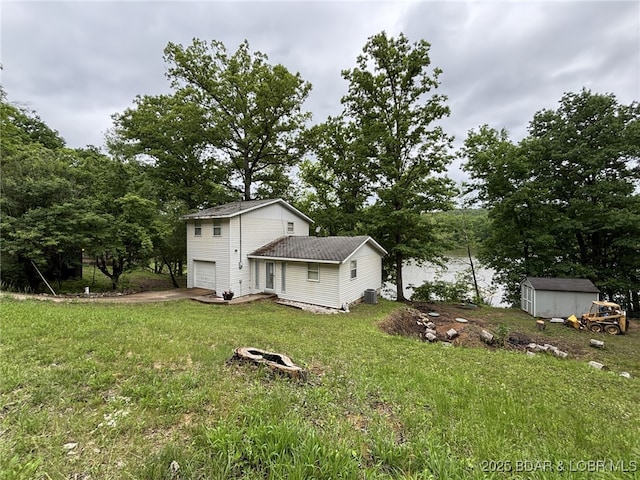 1265 Lick Creek Rd, Edwards, MO 65326 - rear view of property with an attached garage, a storage unit, a lawn, and concrete driveway
