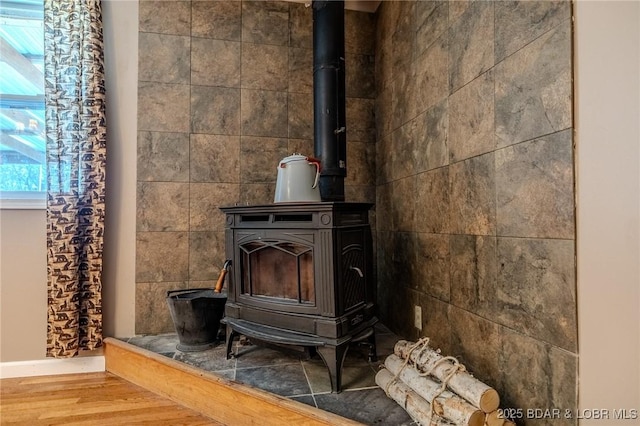 details featuring a wood stove, wood finished floors, and baseboards