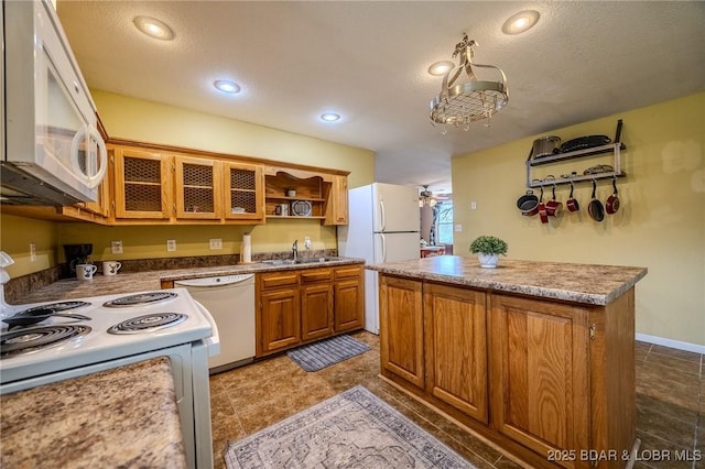 kitchen featuring glass insert cabinets, a sink, white appliances, brown cabinets, and a kitchen island