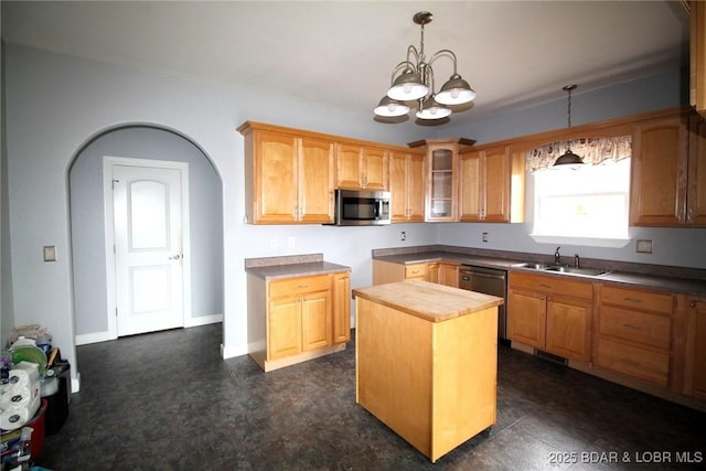 kitchen with glass insert cabinets, appliances with stainless steel finishes, a sink, decorative light fixtures, and a notable chandelier