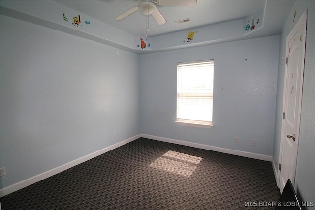unfurnished room featuring visible vents, dark colored carpet, a ceiling fan, and baseboards