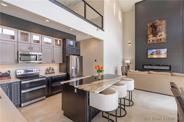 TBD Willow Rd, Eldon, MO 65026 - kitchen with appliances with stainless steel finishes, a breakfast bar, glass insert cabinets, a center island, and a high ceiling