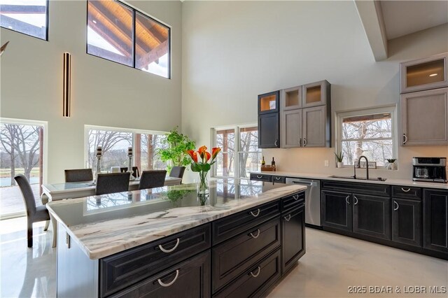 TBD Willow Rd, Eldon, MO 65026 - kitchen featuring dishwasher, a high ceiling, a kitchen island, glass insert cabinets, and light stone counters