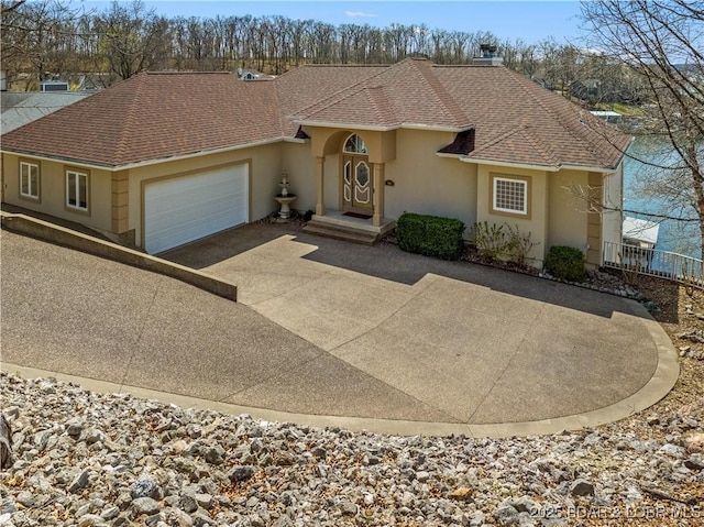 1065 Imperial Point Dr, Four Seasons, MO 65049 - mediterranean / spanish-style home with a shingled roof, stucco siding, driveway, and a garage