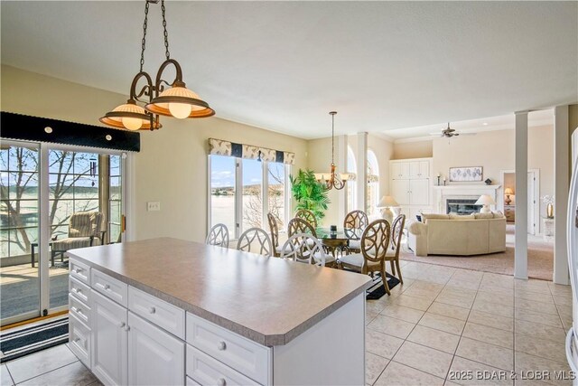 1065 Imperial Point Dr, Four Seasons, MO 65049 - kitchen with light tile patterned floors, healthy amount of natural light, a glass covered fireplace, and white cabinetry