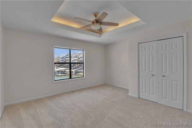 1293 Ginger Rd, Lake Ozark, MO 65049 - unfurnished bedroom featuring a closet, baseboards, a raised ceiling, and carpet floors