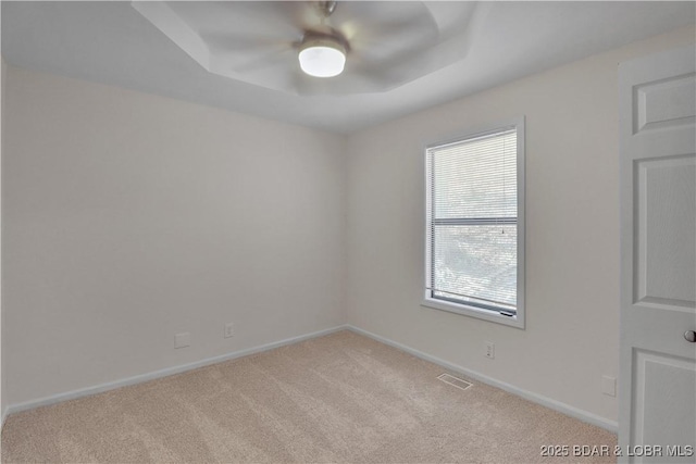 1293 Ginger Rd, Lake Ozark, MO 65049 - spare room with a ceiling fan, a tray ceiling, visible vents, baseboards, and light colored carpet