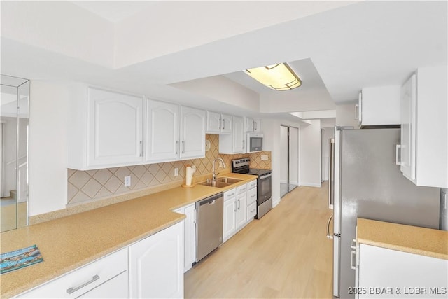 1293 Ginger Rd, Lake Ozark, MO 65049 - kitchen featuring light wood finished floors, a sink, white cabinetry, decorative backsplash, and appliances with stainless steel finishes