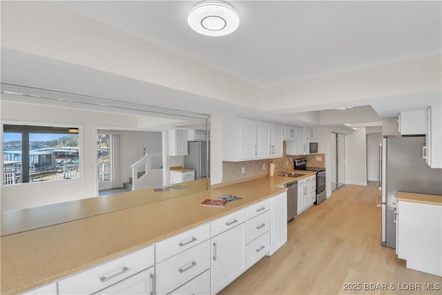 1293 Ginger Rd, Lake Ozark, MO 65049 - kitchen with light wood finished floors, stainless steel appliances, white cabinetry, light countertops, and decorative backsplash