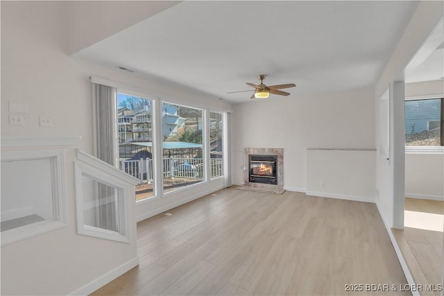 1293 Ginger Rd, Lake Ozark, MO 65049 - unfurnished living room featuring light wood-type flooring, visible vents, baseboards, ceiling fan, and a high end fireplace
