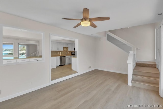 1293 Ginger Rd, Lake Ozark, MO 65049 - unfurnished living room featuring light wood finished floors, baseboards, ceiling fan, and stairs