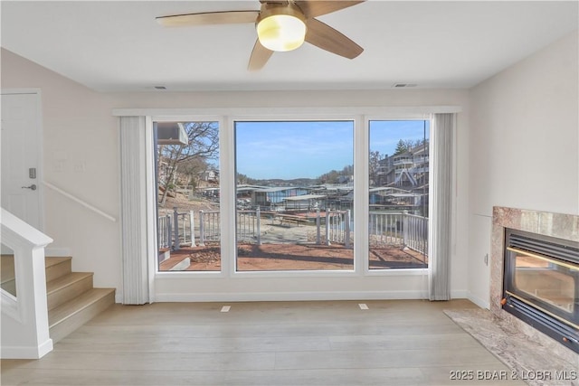 1293 Ginger Rd, Lake Ozark, MO 65049 - unfurnished living room with wood finished floors, a ceiling fan, a premium fireplace, visible vents, and stairs