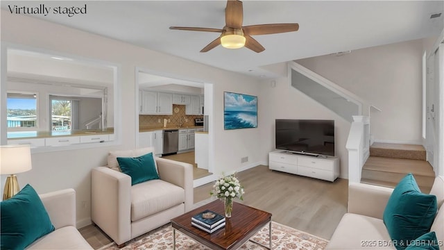 1293 Ginger Rd, Lake Ozark, MO 65049 - living area with stairway, baseboards, visible vents, ceiling fan, and light wood-style floors