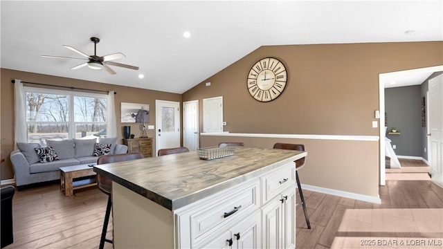 1636 Carol Rd, Lake Ozark, MO 65049 - kitchen featuring a breakfast bar area, a ceiling fan, light wood-style flooring, vaulted ceiling, and white cabinets