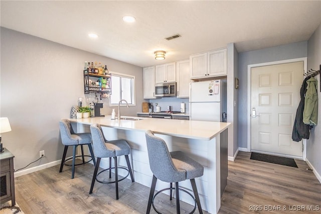 2500 Bay Point Ln Unit 135, Osage Beach, MO 65065 - kitchen with freestanding refrigerator, visible vents, stainless steel microwave, a sink, and a breakfast bar area
