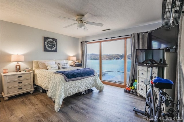 2500 Bay Point Ln Unit 135, Osage Beach, MO 65065 - bedroom featuring dark wood-type flooring, a textured ceiling, a ceiling fan, visible vents, and access to exterior