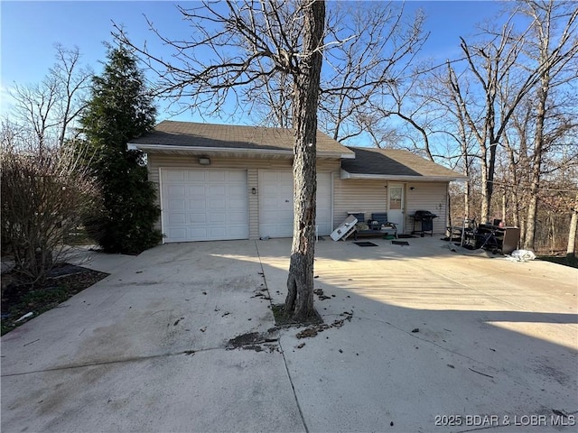 view of side of property featuring concrete driveway and a garage