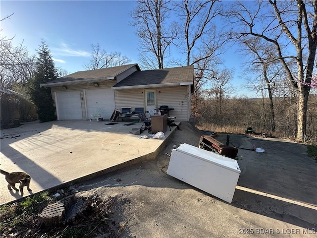 view of side of property featuring a garage, driveway, and a patio area