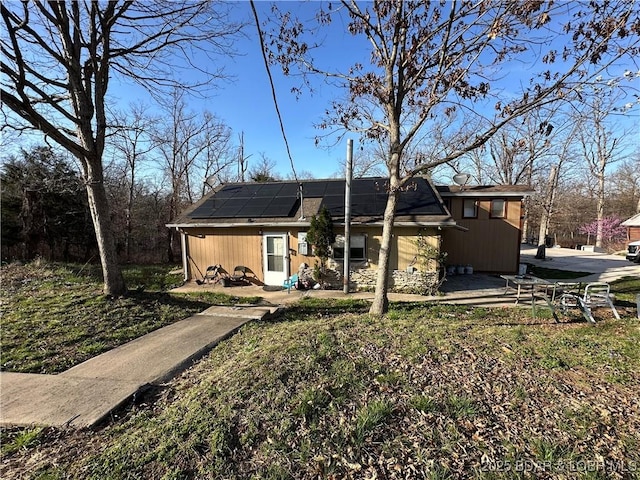 rear view of property with a patio and roof mounted solar panels