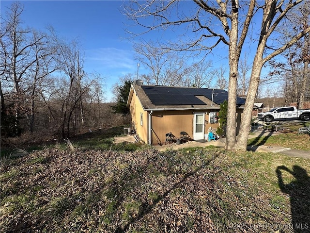 exterior space featuring a shingled roof and roof mounted solar panels