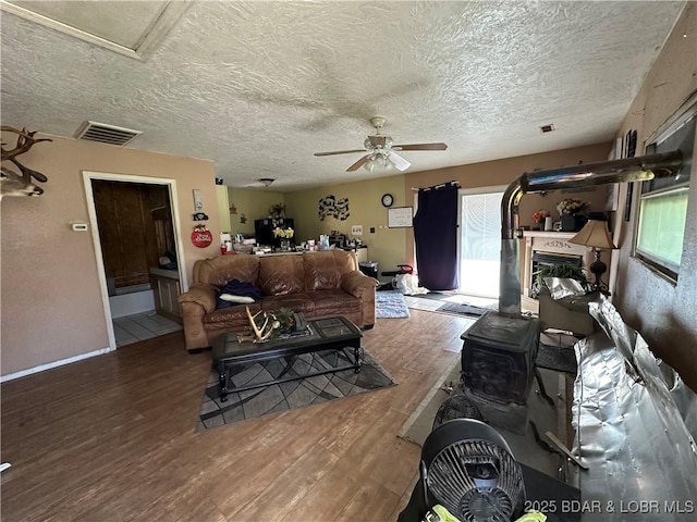 living room featuring a healthy amount of sunlight, visible vents, a ceiling fan, and wood finished floors