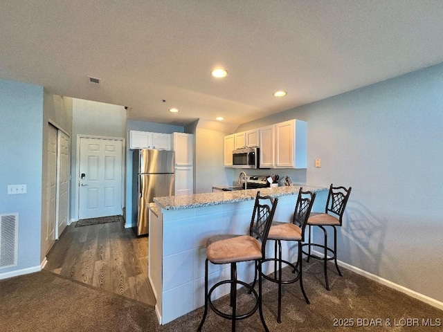 1481 Ledges Dr Unit 1046, Osage Beach, MO 65065 - kitchen with light stone countertops, baseboards, a peninsula, white cabinets, and appliances with stainless steel finishes