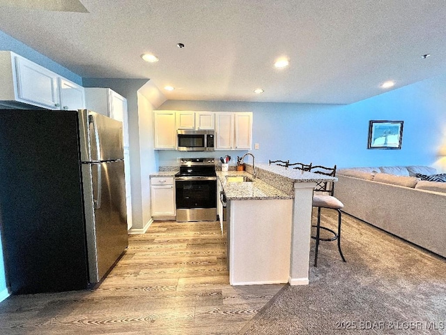 1481 Ledges Dr Unit 1046, Osage Beach, MO 65065 - kitchen featuring a breakfast bar, a sink, a peninsula, stainless steel appliances, and light wood-type flooring
