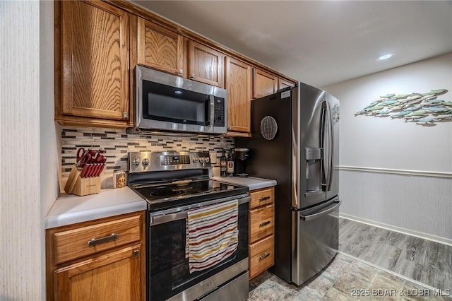 251 Vision Dr Unit 1D, Camdenton, MO 65020 - kitchen featuring light countertops, appliances with stainless steel finishes, brown cabinetry, backsplash, and a wainscoted wall