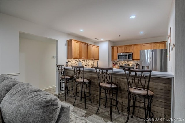 251 Vision Dr Unit 1D, Camdenton, MO 65020 - kitchen featuring a peninsula, appliances with stainless steel finishes, backsplash, and a kitchen breakfast bar