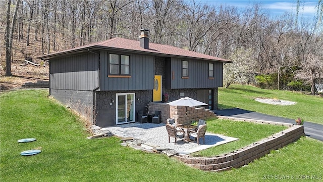 83 Archer Dr, Camdenton, MO 65020 - back of property featuring a patio, a chimney, stone siding, an attached garage, and a yard