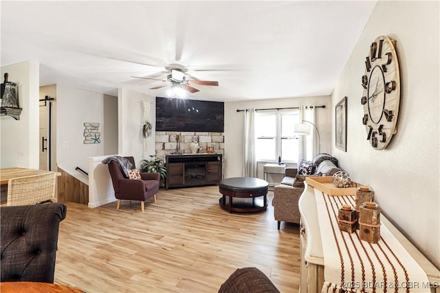 83 Archer Dr, Camdenton, MO 65020 - living room with a fireplace, a ceiling fan, a barn door, light wood finished floors, and baseboards