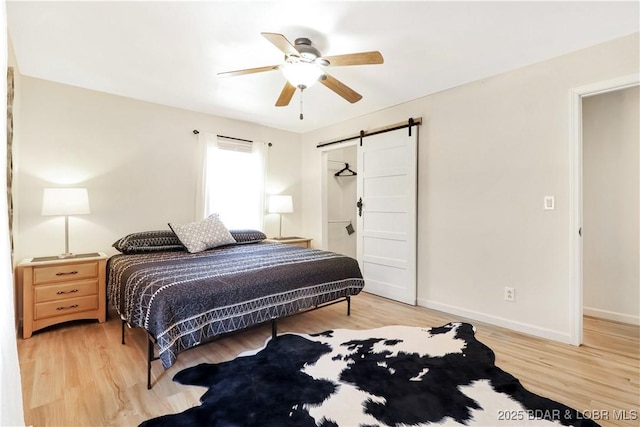 83 Archer Dr, Camdenton, MO 65020 - bedroom with light wood-style flooring, a ceiling fan, a barn door, and baseboards