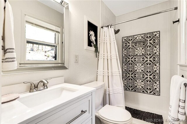 83 Archer Dr, Camdenton, MO 65020 - bathroom featuring a tile shower, a textured wall, vanity, and toilet