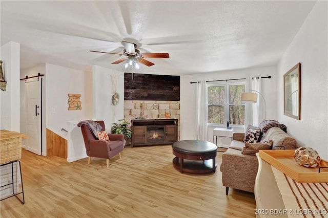 83 Archer Dr, Camdenton, MO 65020 - living room with light wood-type flooring, a ceiling fan, a barn door, and a fireplace