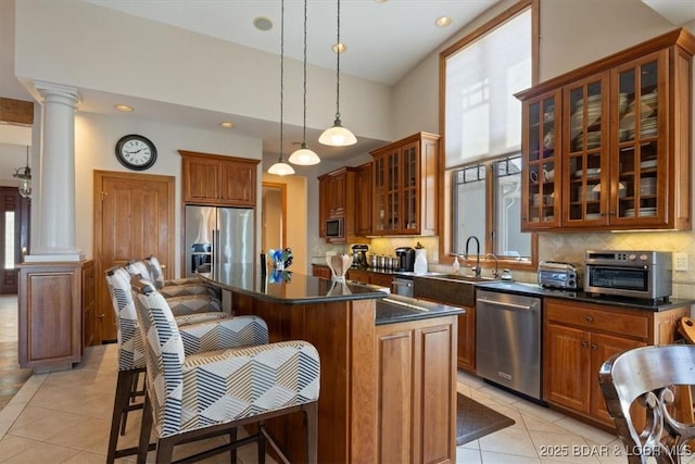 406 N Point Dr, Camdenton, MO 65020 - kitchen featuring stainless steel appliances, decorative columns, light tile patterned flooring, a sink, and a kitchen breakfast bar