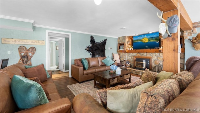 living room with a stone fireplace, ornamental molding, and wood finished floors